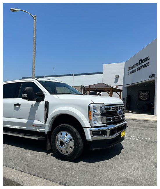 Powerstroke Engine Oil Leak Repair Services in Chino, CA at Domestic Diesel and Automotive Services. Image of a white heavy-duty truck, equipped with a 6.7L Powerstroke engine, parked at Domestic Diesel & Auto Service for expert oil leak inspection.